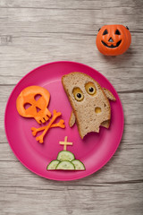 Halloween ghost and skull made of bread and carrot on board