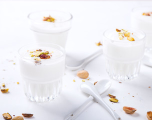 Yogurt in glass cups with nuts,pistachios.Breakfast,Dessert, Pudding on a white background.Food or Healthy diet concept.selective focus.Top view.