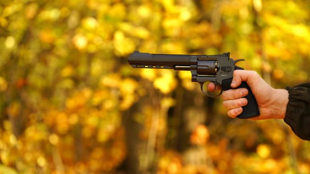 footage a man firing a revolver outdoors autumn. 4K