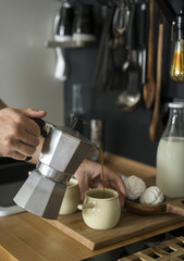 Morning coffee. Man pouring coffee into a cup of geyser coffeemakers in the kitchen at home.