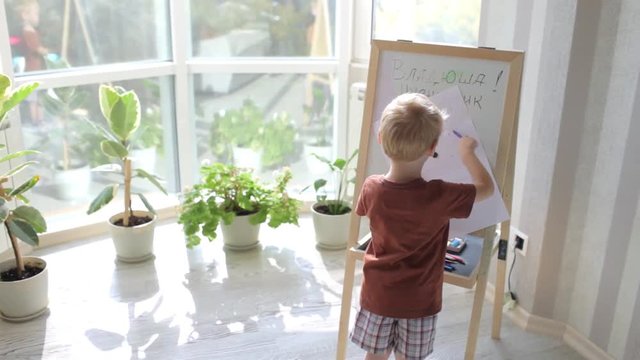 Boy Draws a Marker on the Easel by the Window