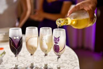 Hand man pours champagne into wedding glasses