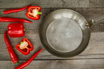 Red Hot Chili Peppers and pan on vintage wooden board. Top view with copy space.