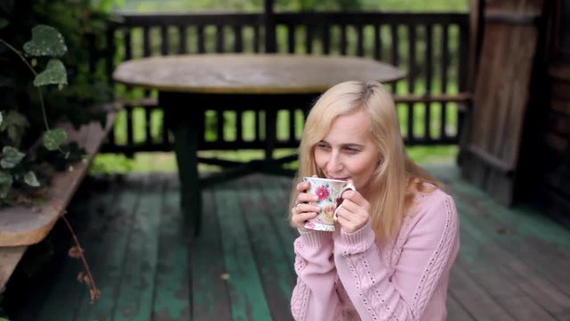 Woman Drinking Tea Sitting On An Old Porch