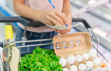  women  checking her grocery list in the supermarket