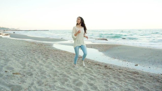 Pretty young happy woman running at the beach, having fun