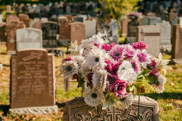Flowers in a cemetery with headstones in the background at sunset