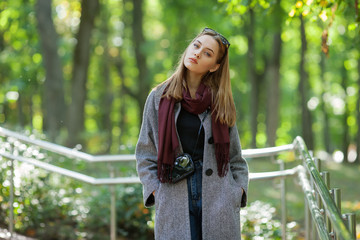 Beautiful stylish young woman in a warm scarf blue jeans trendy cozy coat walking along in fall city park