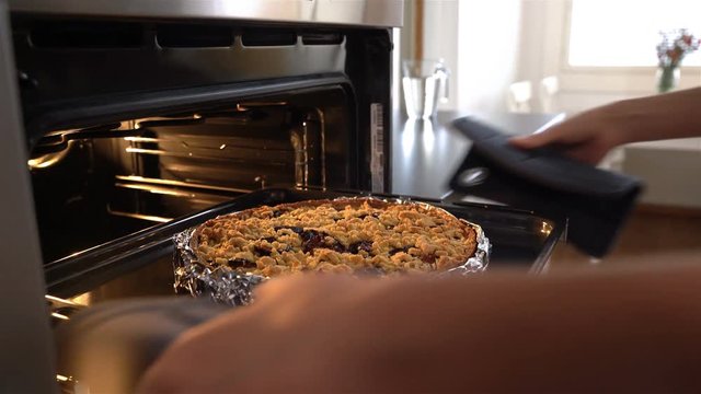 Young attractive housewife gets out of the oven delicious hot pie. Dolly shot.