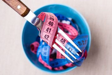 Many colorful measuring tapes in bowl on table