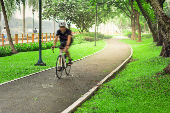 Male cyclist cycling on path cycling in public park in the morni