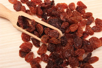 Brown raisins with spoon on wooden table, healthy eating