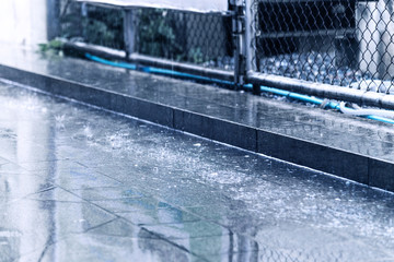 close up rain water drop falling in city street floor with the w
