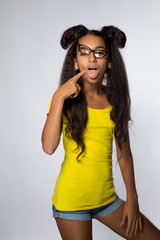 Emotional young brunette girl with long hair in yellow shirt and glasses on a white background