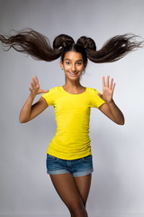 Emotional young brunette girl with long hair in yellow shirt on a white background