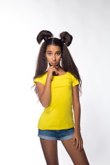 Emotional young brunette girl with long hair in yellow shirt on a white background