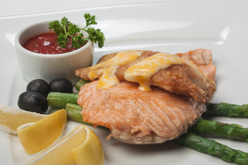 Fish with mayonnaise, served with asparagus, olives, lemon and k