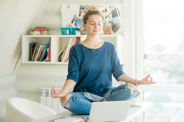 Portrait of an attractive woman on the working table. Lotus pose. Motivation photo