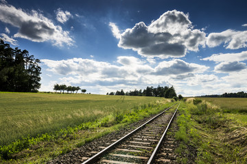 Obraz na płótnie Canvas Empty Rail Track with Blue Sky and Green Field
