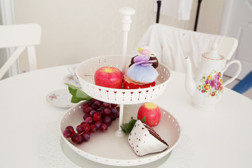 Close-up of artificial grape bunches, apple and cake in white  p