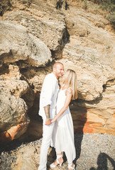 Young models couple posing on the beach with stones