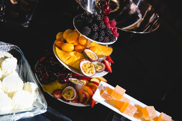 Exotic fruits and berries lie on the white layered serving dish
