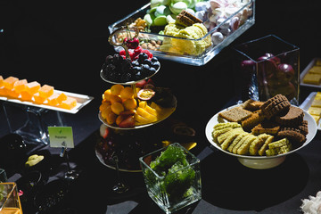 Tasty sweets and fruits served on a black buffet