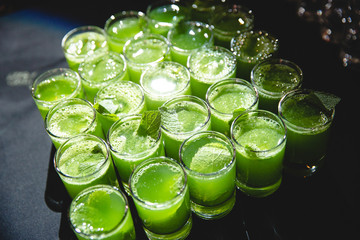 Green shots with mint stand on black tablecloth