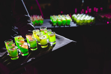 Man holds a black tray with green shots