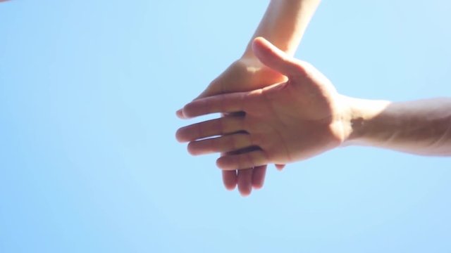 Successful team: many hands holding together on sky background in slowmotion. 1920x1080
