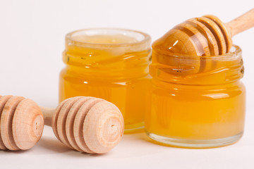 Honey dripping from a wooden honey dipper isolated on white background