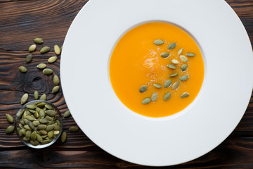 Above view of pumpkin cream-soup in a white glass plate