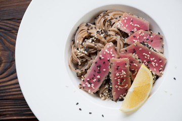Close-up of soba noodles and sliced tuna fillet in a glass plate