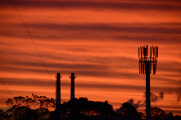 Vivid red sunset behind industrial silhouette