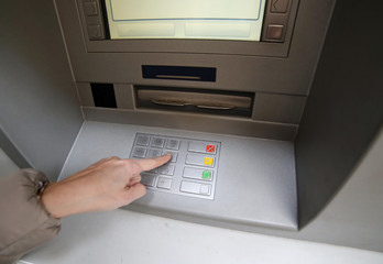 hand of woman while enter the secret code in the door of the atm