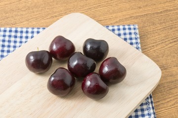 Group of Red Plums on Wooden Cutting Board