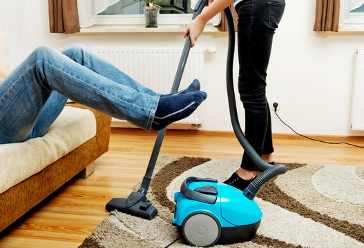 Woman Vacuuming Carpet Man Holding Legs In The Air