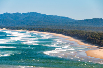 Aerial view of Australian coastal sand beach with mountains on the background. Nambucca Heads, NSW, Australia