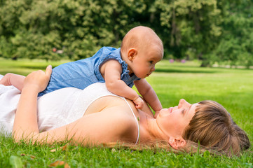 Mother and her baby lying on the grass in park