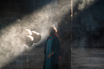 Obraz premium Portrait of graduate girl holding black balloon with sunlight and shadow inside a deserted godown