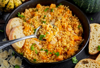 Pumpkin risotto in spoon closeup. iron pan, Parmesan cheese, bread.