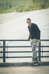 young fit man with inline skates rest in summer park after workout outdoor rollerskater