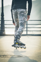 Rollerskater inline in action. Male legs shod in roller skates ride along the promenade
