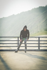 young man with inline skates ride in summer park seafront outdoor rollerskater