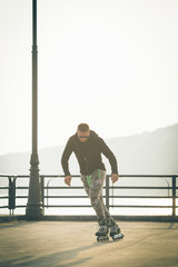 young man with inline skates ride in summer park seafront outdoor rollerskater