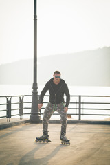 young man with inline skates ride in summer park seafront outdoor rollerskater
