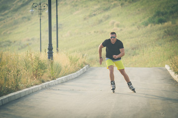 young man with inline skates ride in summer park outdoor rollerskater