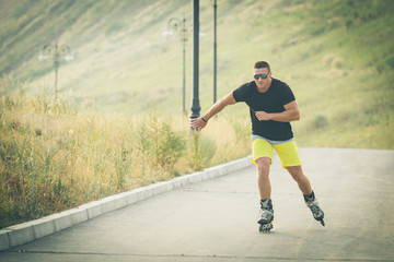 young man with inline skates ride in summer park outdoor rollerskater