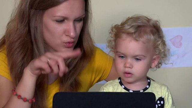 Pretty nanny woman and little child using tablet computer.