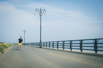 young man with inline skates ride in summer park seafront outdoor rollerskater